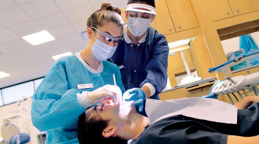 卡姆登县牙科学院的学生正在给病人清洗牙齿